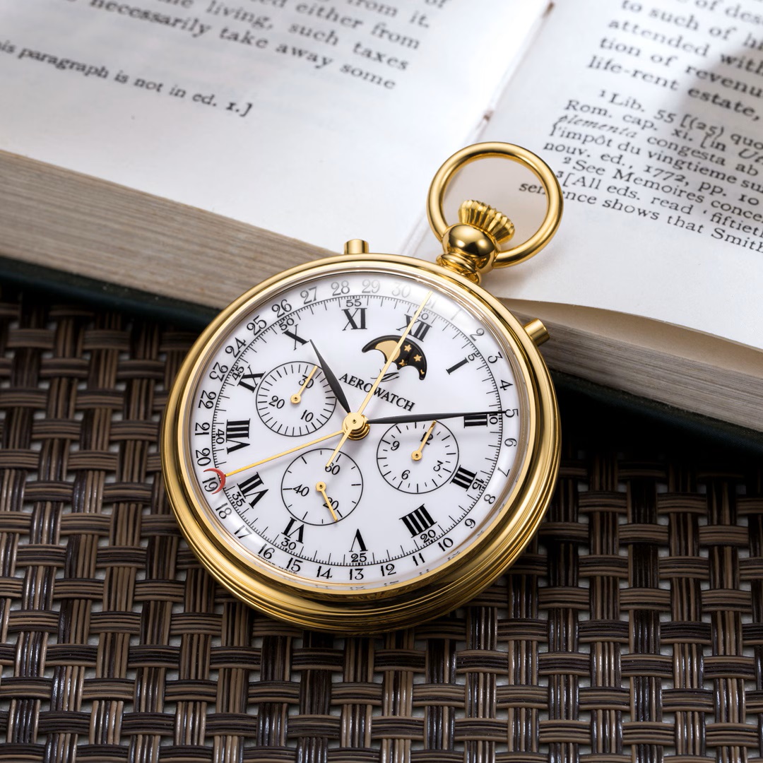 Montre de poche Aérowatch plaquée or sur livre ouvert